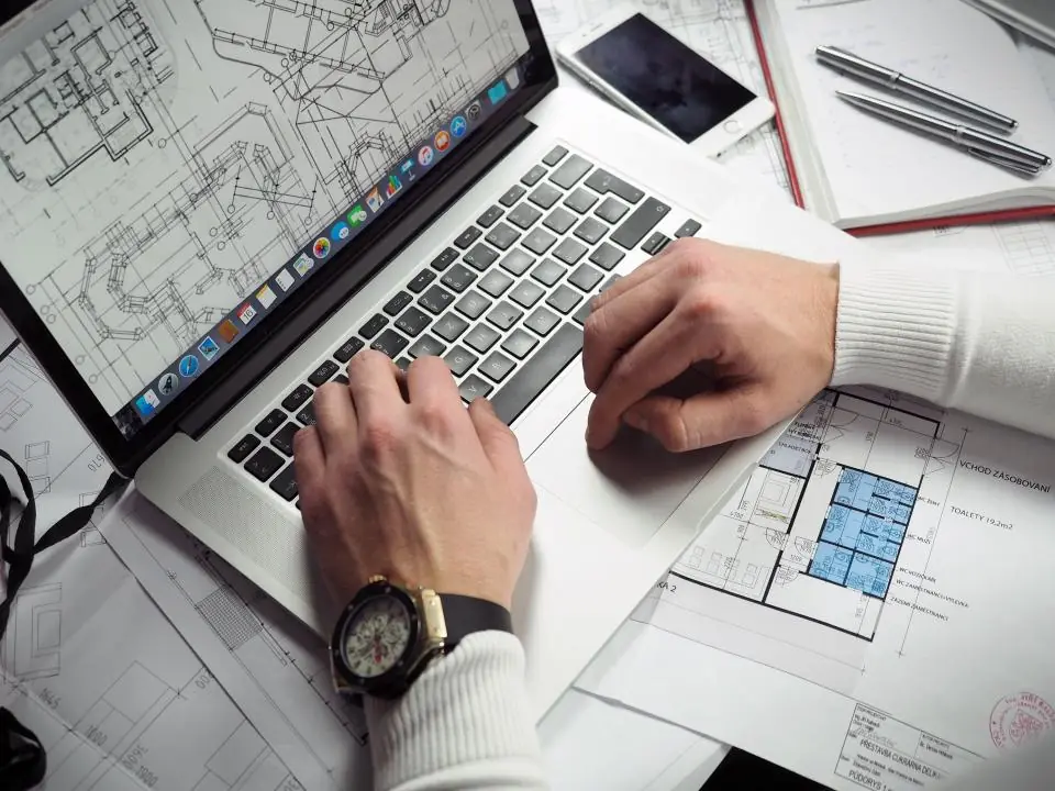 Un architecte travaille sur des plans, ordinateur ouvert